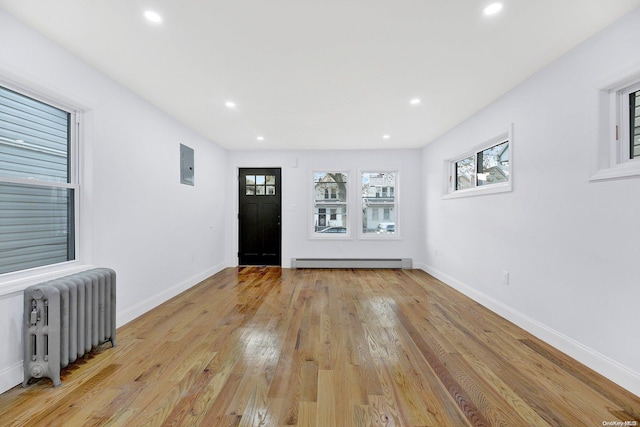 entrance foyer with electric panel, light wood-type flooring, radiator, and a baseboard heating unit