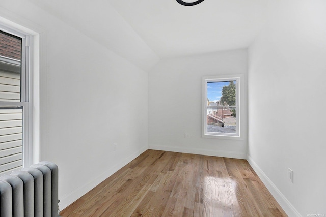 additional living space with lofted ceiling, light wood-type flooring, and radiator heating unit