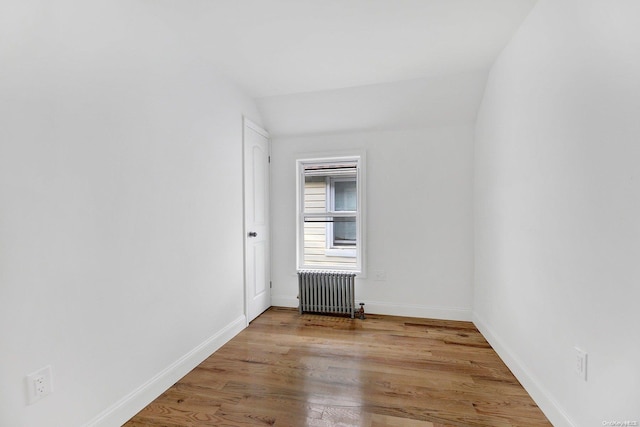 spare room with wood-type flooring, radiator, and vaulted ceiling