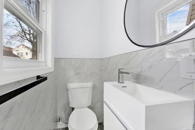 bathroom with vanity, toilet, and tile walls