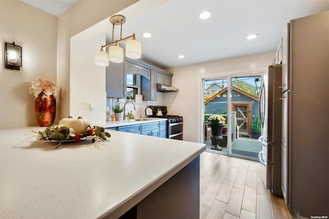 kitchen with sink, tasteful backsplash, decorative light fixtures, light hardwood / wood-style floors, and stainless steel appliances