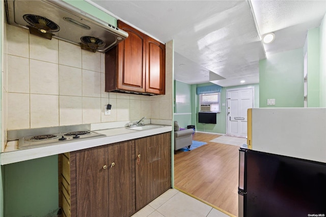 kitchen with sink, white stovetop, ventilation hood, backsplash, and light wood-type flooring