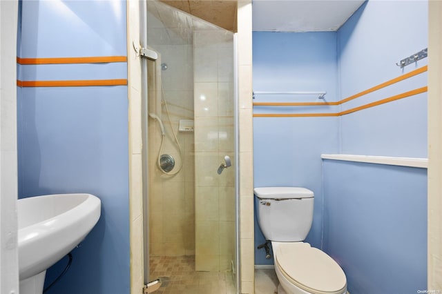 bathroom with toilet, a shower with shower door, and sink