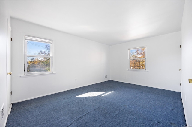 spare room featuring dark carpet and plenty of natural light