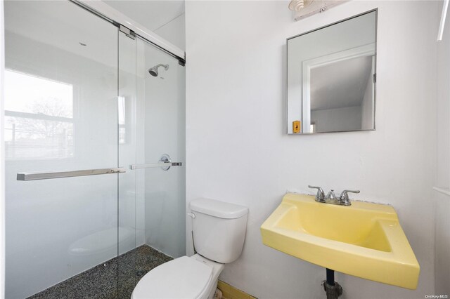 bathroom featuring sink, a shower with shower door, and toilet