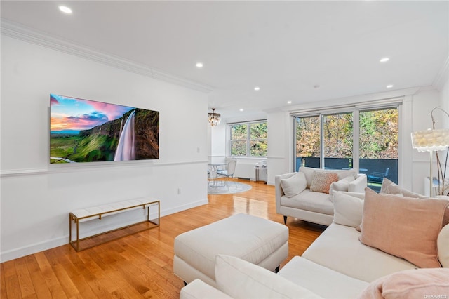 living room with an inviting chandelier, light hardwood / wood-style floors, and ornamental molding