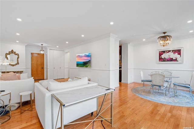 living room featuring a chandelier, light wood-type flooring, and ornamental molding