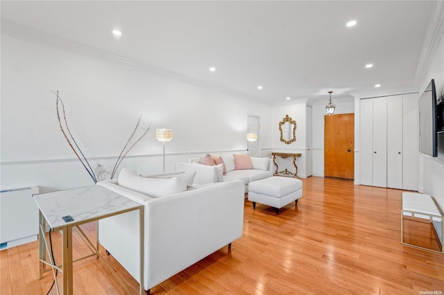 living room with radiator heating unit, light hardwood / wood-style flooring, and ornamental molding