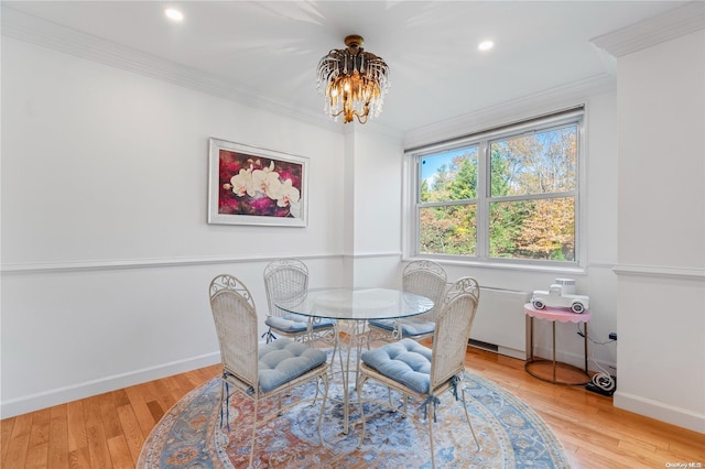 dining room featuring ornamental molding, light hardwood / wood-style flooring, and a notable chandelier