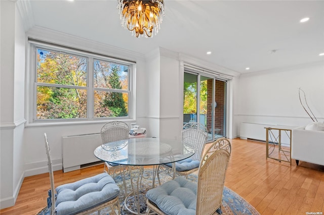 dining space with light hardwood / wood-style flooring, a chandelier, and ornamental molding