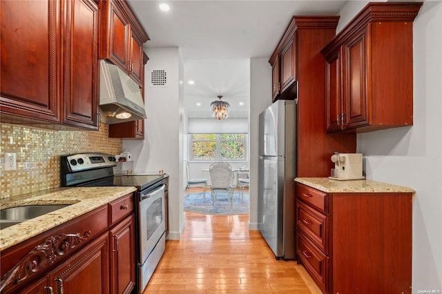 kitchen featuring decorative backsplash, light stone countertops, light wood-type flooring, and appliances with stainless steel finishes