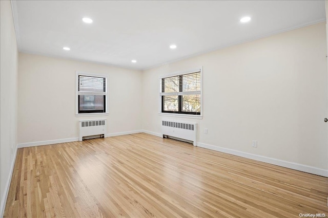 unfurnished living room with radiator heating unit, light hardwood / wood-style flooring, and crown molding