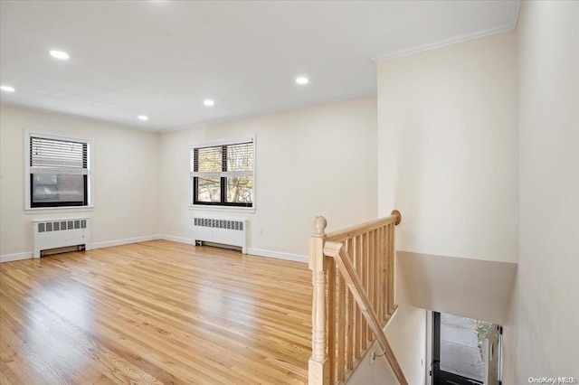 unfurnished living room featuring radiator heating unit, light wood-type flooring, and ornamental molding