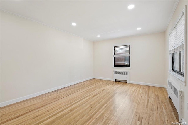 unfurnished living room with radiator, ornamental molding, and light wood-type flooring