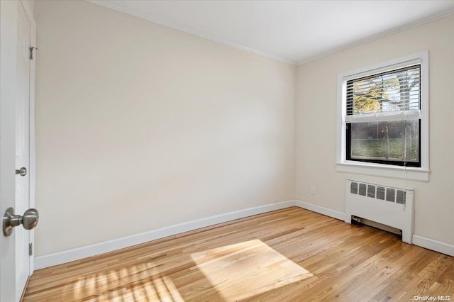 empty room with light hardwood / wood-style floors, radiator, and ornamental molding