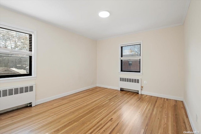 spare room featuring plenty of natural light, radiator, and light hardwood / wood-style flooring