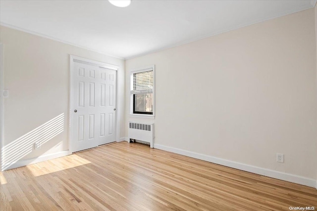 unfurnished room featuring light hardwood / wood-style floors, ornamental molding, and radiator