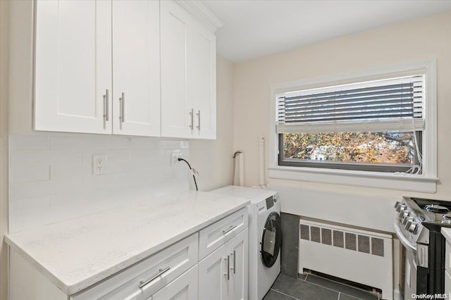 clothes washing area featuring dark tile patterned flooring, washer / clothes dryer, and radiator