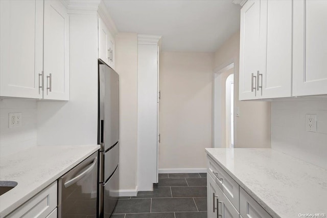 kitchen featuring white cabinets, light stone counters, stainless steel appliances, and dark tile patterned flooring