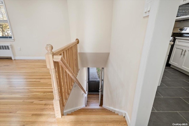 stairway featuring radiator heating unit and wood-type flooring