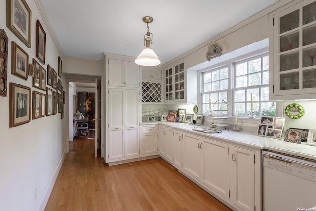 kitchen featuring white dishwasher, light hardwood / wood-style floors, hanging light fixtures, and white cabinets