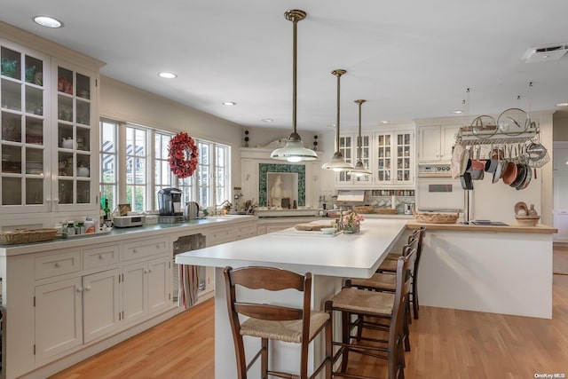 kitchen featuring kitchen peninsula, light wood-type flooring, a kitchen breakfast bar, and pendant lighting