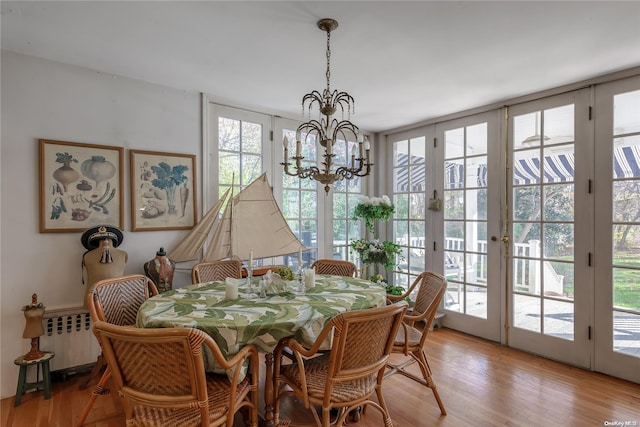 dining space featuring radiator, french doors, an inviting chandelier, and light hardwood / wood-style flooring