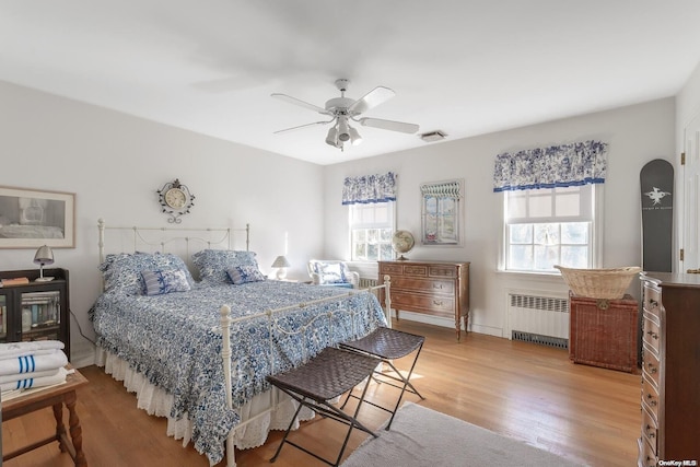 bedroom featuring ceiling fan, radiator, and hardwood / wood-style flooring