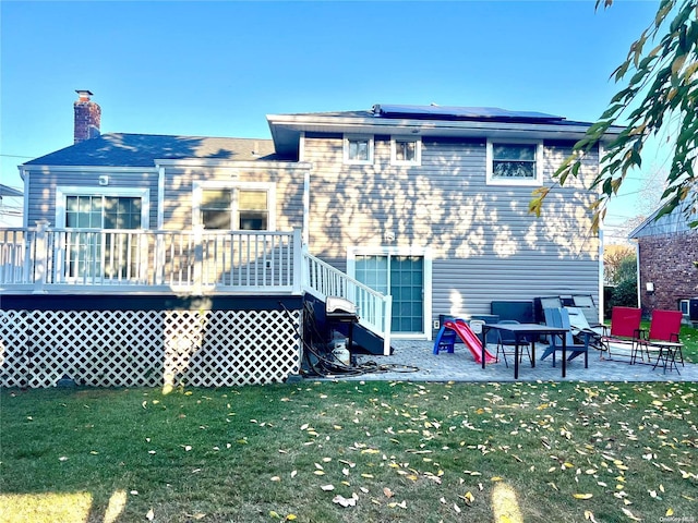 back of house featuring solar panels, a patio, a deck, and a yard