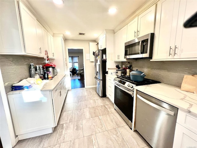 kitchen with decorative backsplash, light stone counters, white cabinetry, and stainless steel appliances