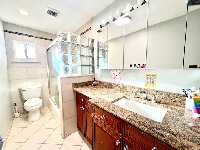 bathroom featuring vanity, a shower with door, tile walls, tile patterned flooring, and toilet