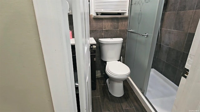 bathroom with radiator heating unit, toilet, tile walls, and a shower with shower door