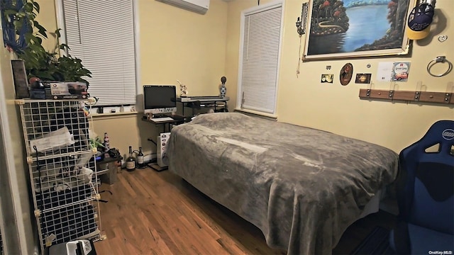 bedroom with a wall mounted air conditioner and dark wood-type flooring