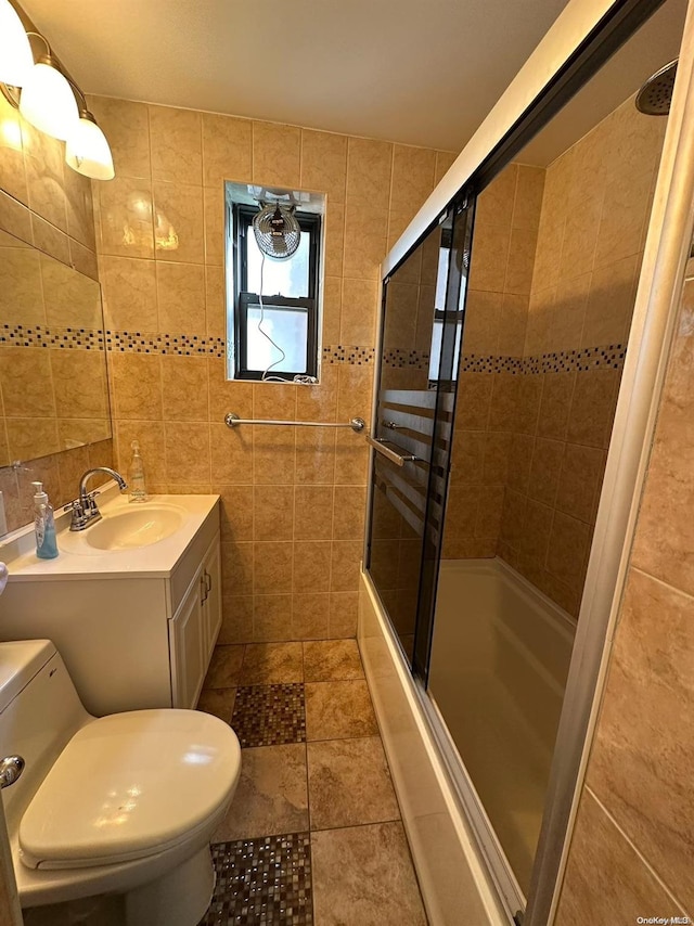 full bathroom with tile patterned floors, combined bath / shower with glass door, toilet, vanity, and tile walls