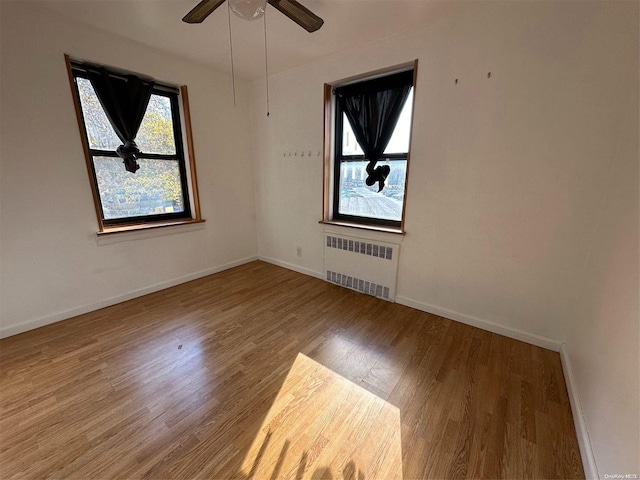 spare room with hardwood / wood-style flooring, ceiling fan, and radiator