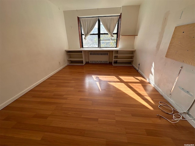 unfurnished room featuring radiator and light hardwood / wood-style flooring