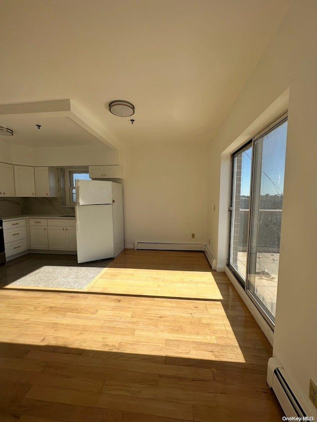 kitchen with white cabinets, light wood-type flooring, a baseboard heating unit, and white refrigerator