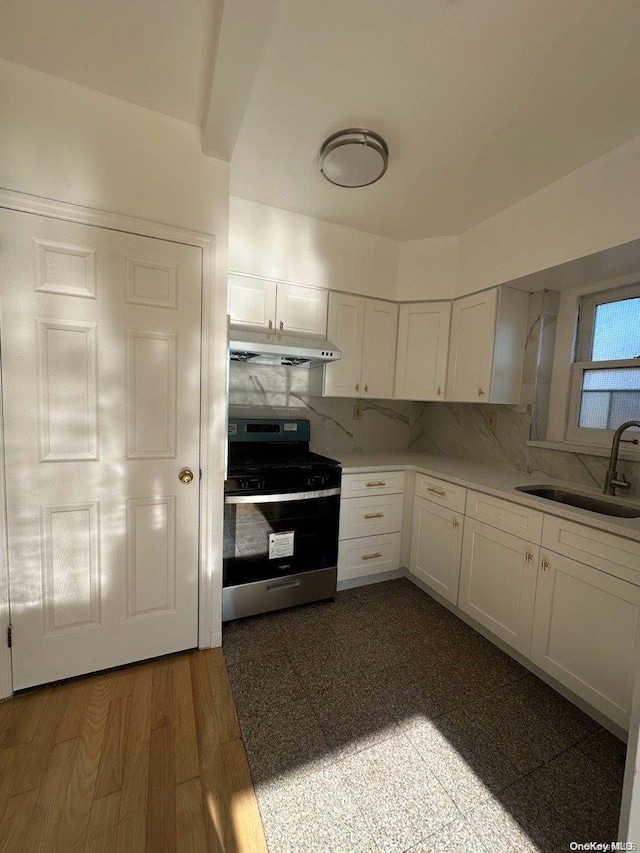 kitchen with sink, dark hardwood / wood-style floors, stainless steel range, tasteful backsplash, and white cabinetry