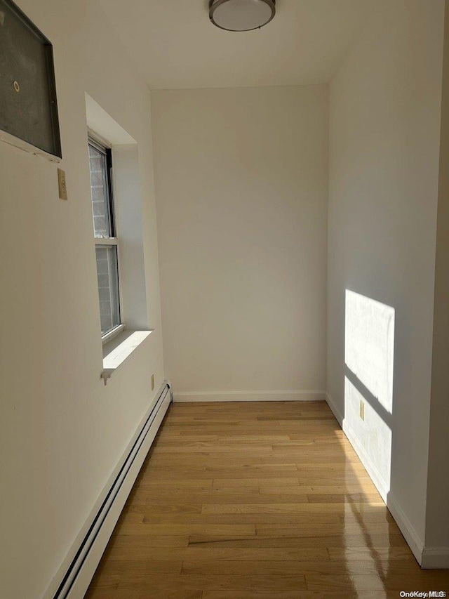 empty room featuring a baseboard radiator and light wood-type flooring