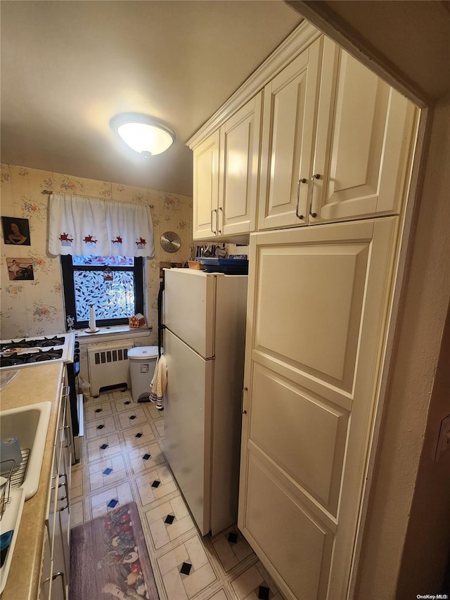 kitchen with radiator, white cabinets, and fridge