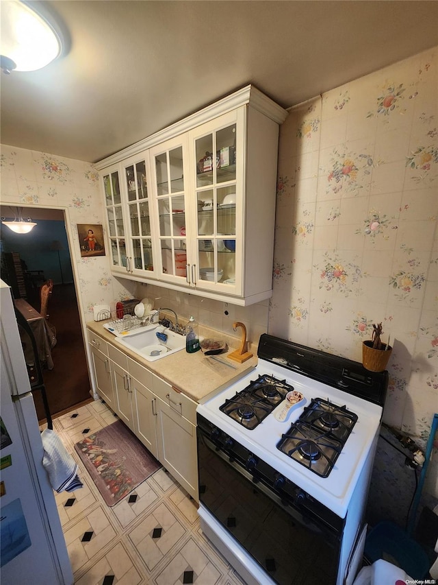 kitchen with white cabinets, sink, and white range with gas cooktop