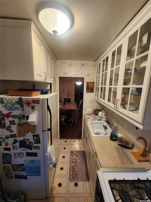 kitchen with white cabinetry, white appliances, and sink