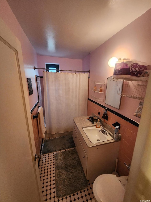 bathroom featuring a shower with curtain, tile patterned flooring, toilet, vanity, and tile walls