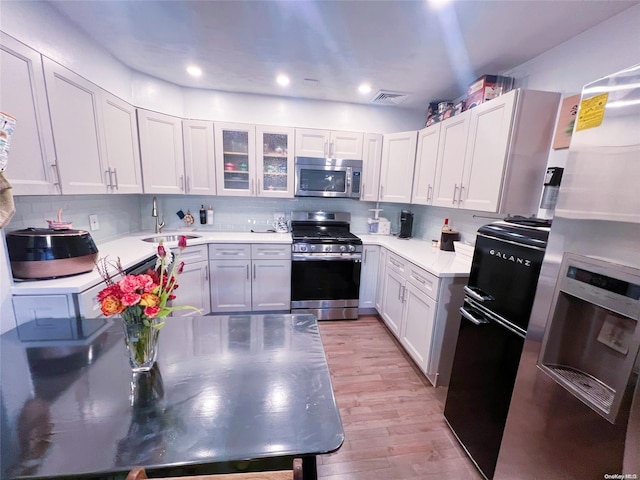 kitchen with white cabinets, sink, appliances with stainless steel finishes, and light hardwood / wood-style flooring