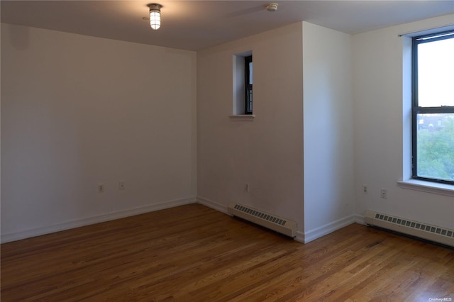 spare room featuring hardwood / wood-style floors, a baseboard radiator, and plenty of natural light