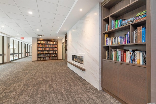 interior space featuring a large fireplace, carpet floors, built in features, and a paneled ceiling