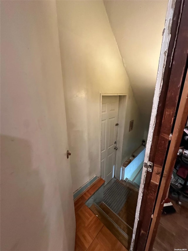 stairs featuring vaulted ceiling and parquet flooring