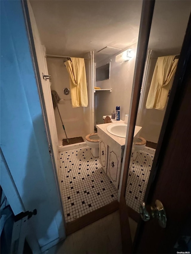 bathroom with a shower, tile patterned flooring, vanity, and toilet