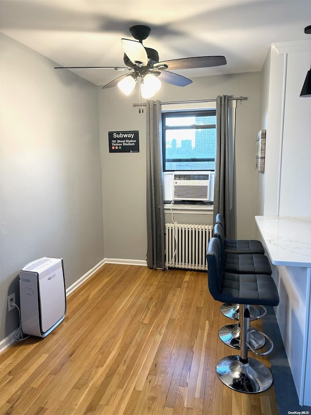 interior space with radiator heating unit, ceiling fan, cooling unit, and hardwood / wood-style floors