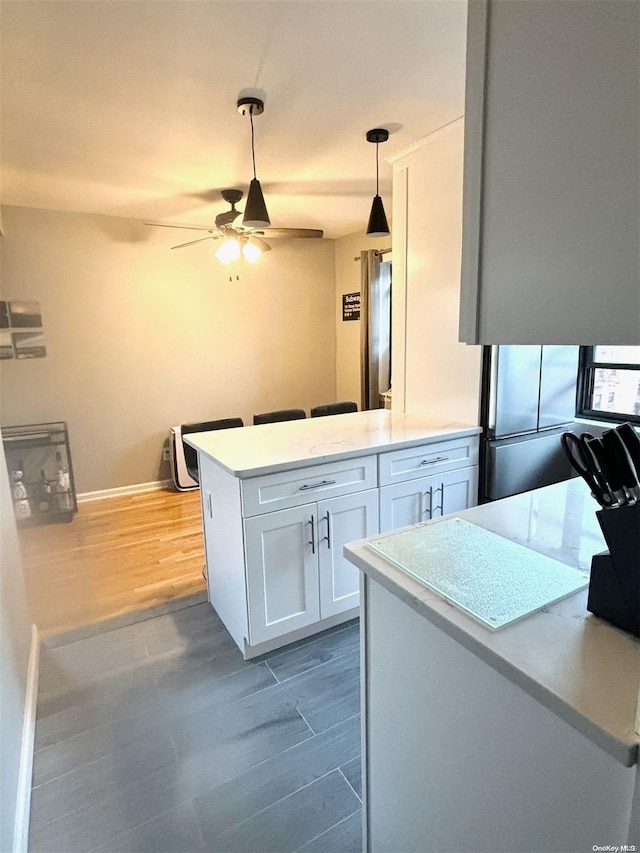 kitchen featuring kitchen peninsula, ceiling fan, dark hardwood / wood-style floors, white cabinetry, and hanging light fixtures